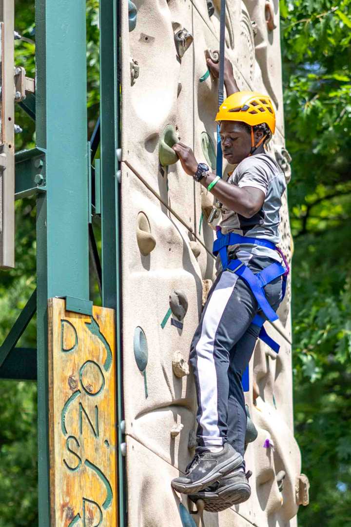 A North Star camper works his way up the climbing wall on a sunny afternoon.