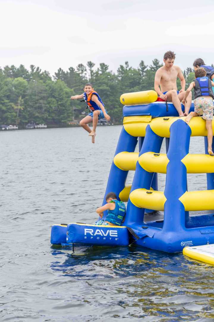 A camper leaps from the lakefront climbing tower into the water on a hot summer day