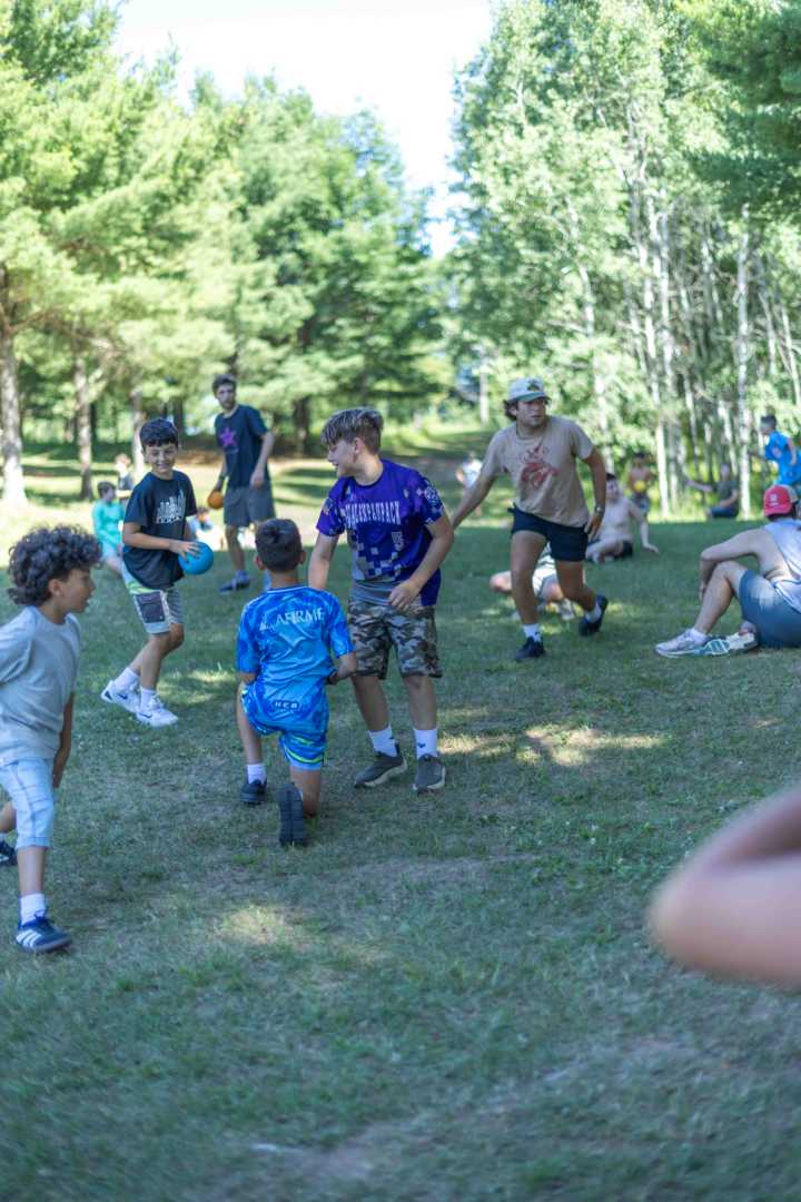 Campers playing dodgeball in the shade on a hot summer day
