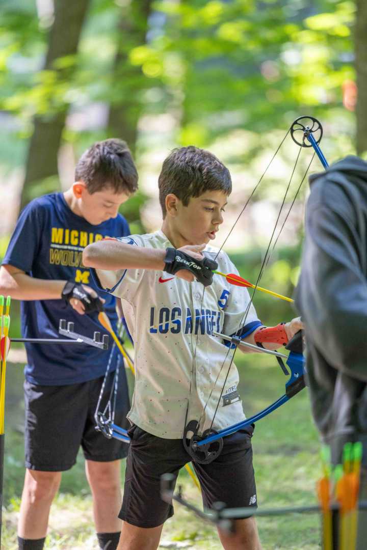 A camper practices archery during an instructional activity period at camp