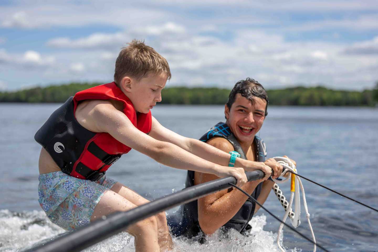 An older camper helping a younger camper learn a new skill at summer camp