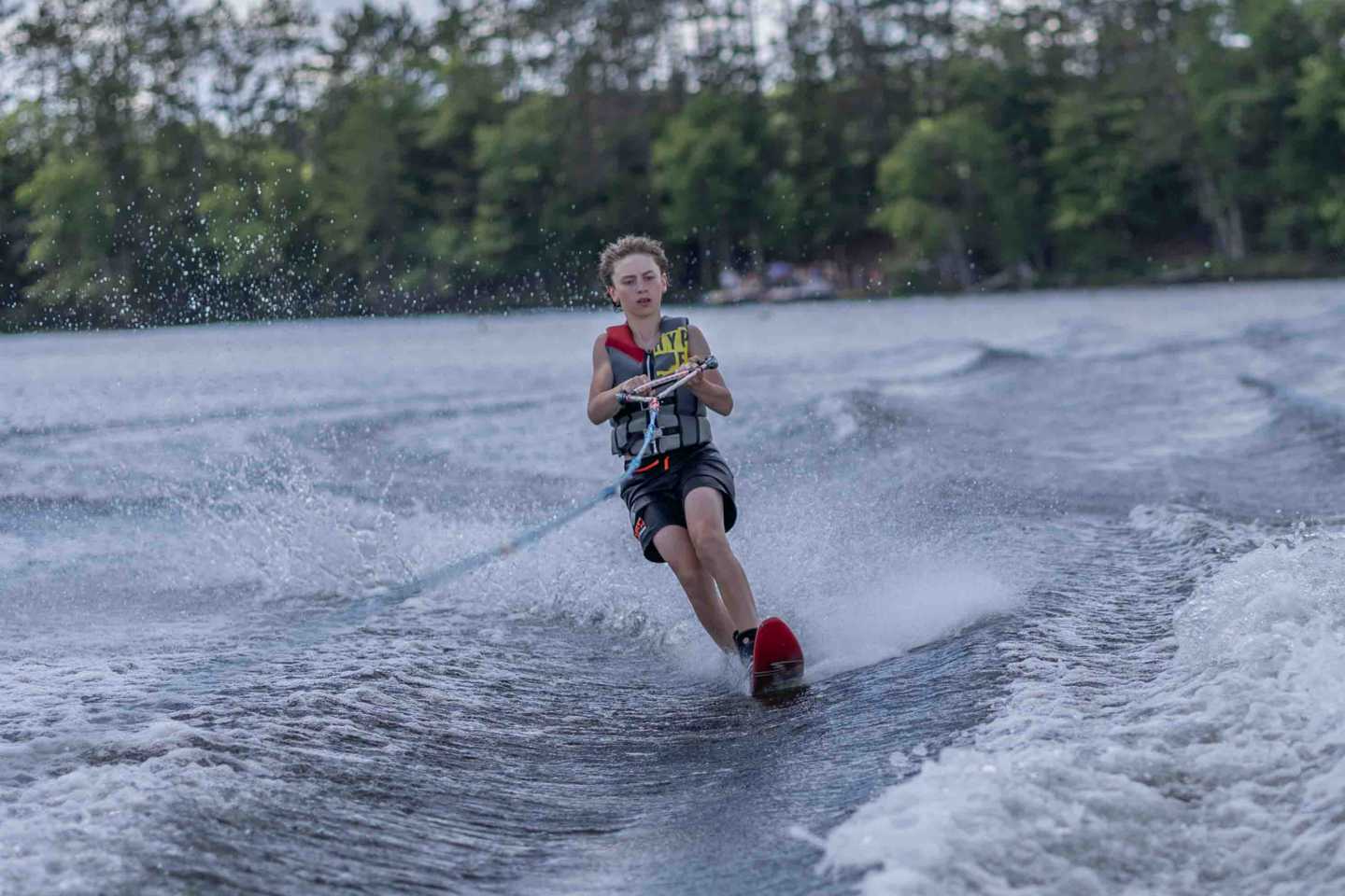 A camper carves across Spider Lake on water skis during an afternoon activity.